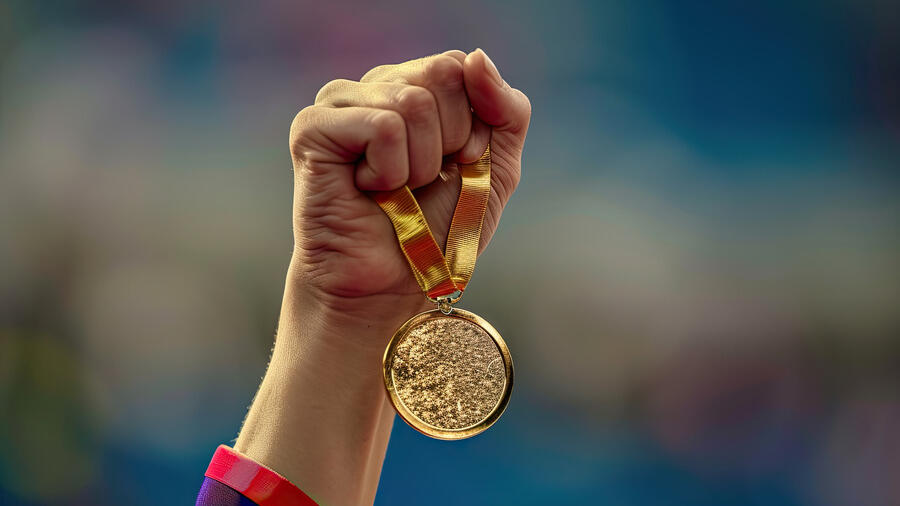 Illustration montrant la main d'une sportive brandissant une médaille d'or olympique